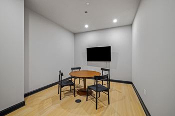 a room with a table and chairs and a television on the wall